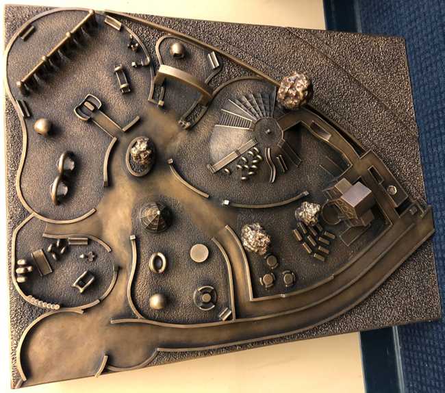 Picture of a bronze map of the Magical Bridge playground with 3D play structures and trees